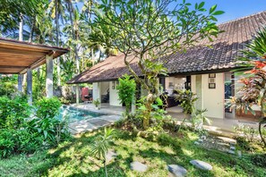 A house with a tiled roof, a swimming pool, and lush greenery.