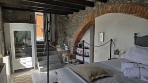 A bedroom with a bed, a desk, and a chair. There is a staircase leading to another room. - Madüneta 5 Terre Guesthouse (Vernazza)