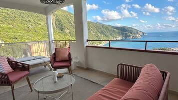 Ein Balkon mit Korbmöbeln, einer gepolsterten Couch und einer hängenden Leuchte.