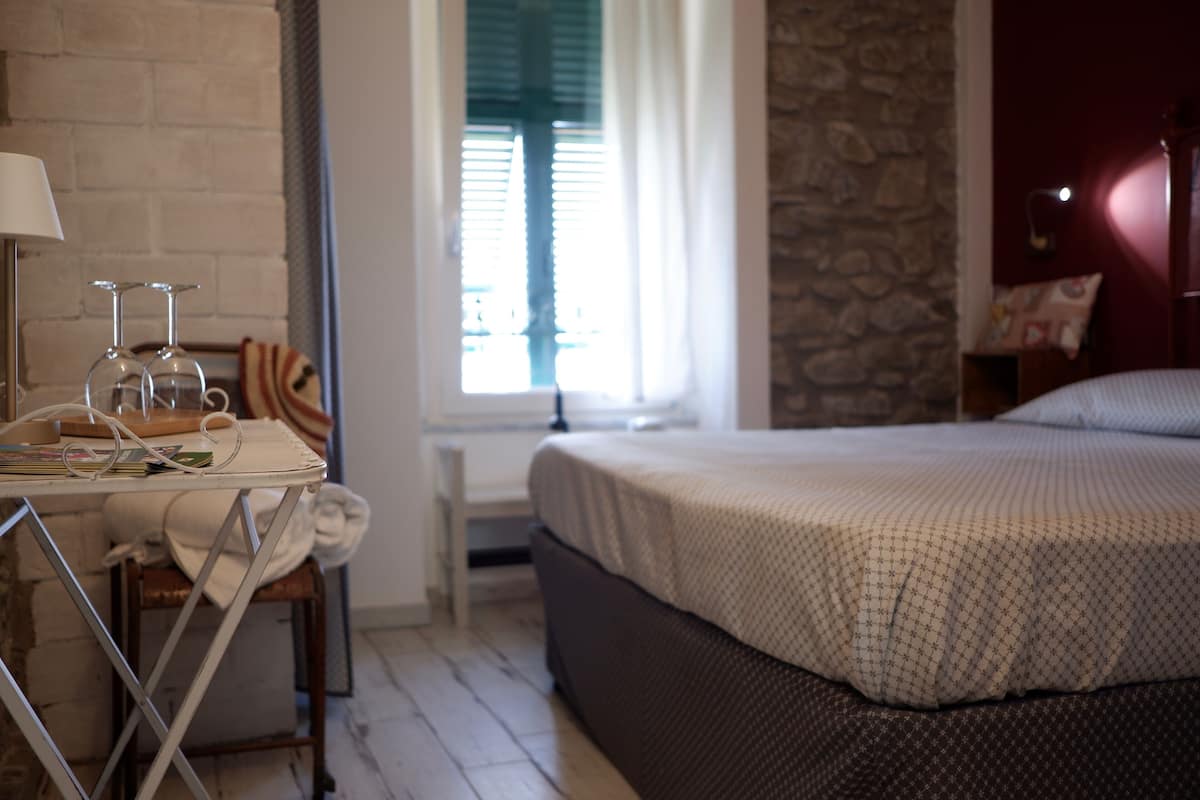 A bedroom with a bed, a desk with a lamp, and a window with curtains.