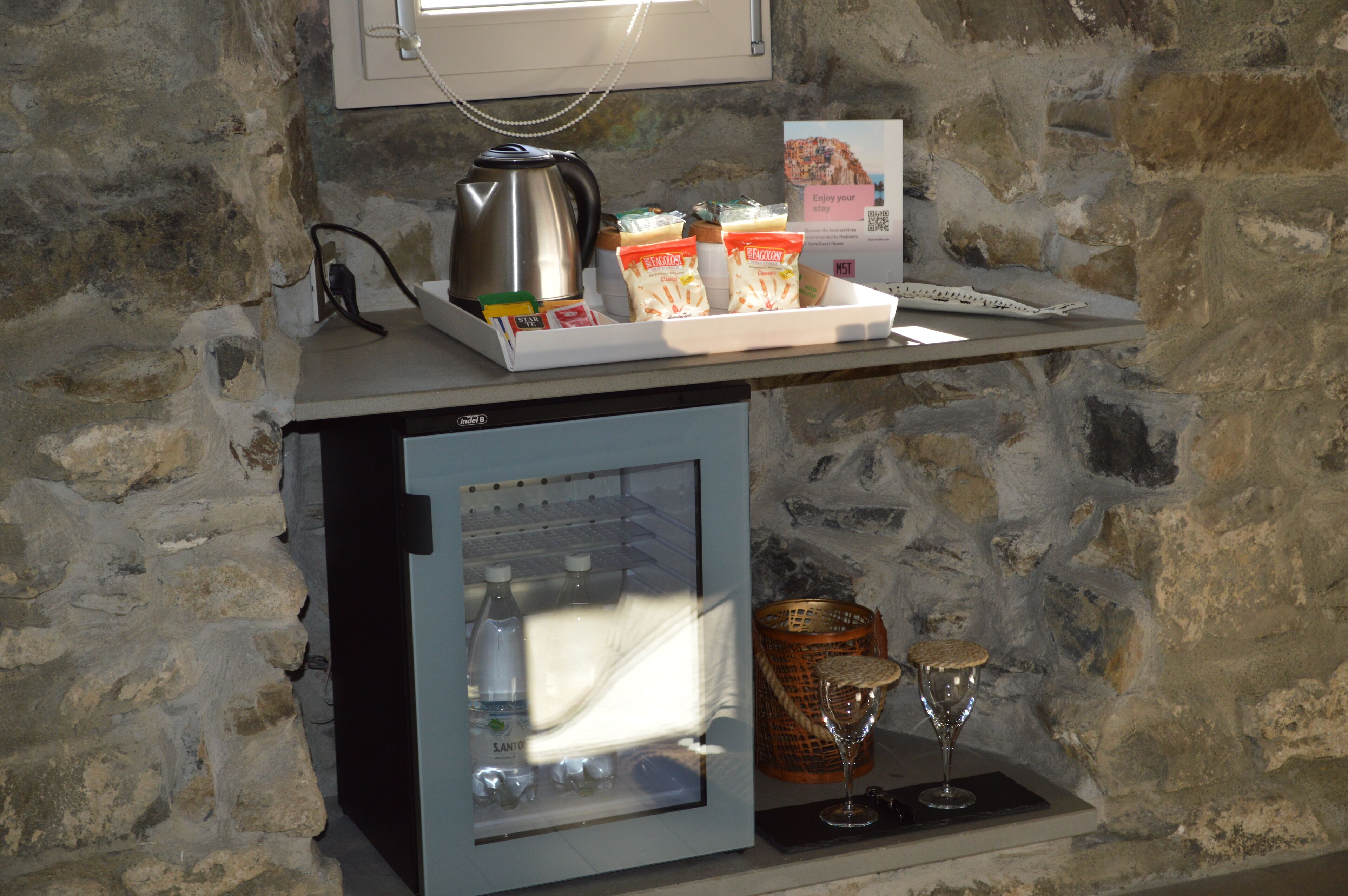 A minibar with a coffee maker, bottled water, snacks, and a glass.