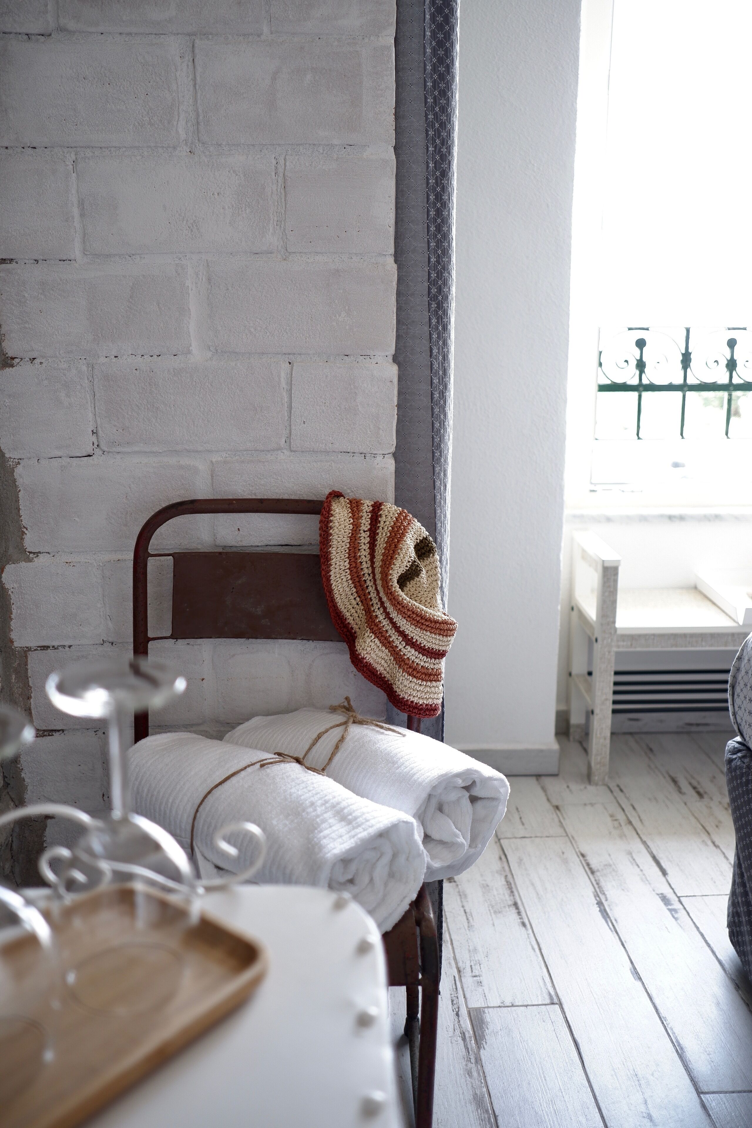 A room with a metal-framed bed, a white wall, and a wooden floor.
