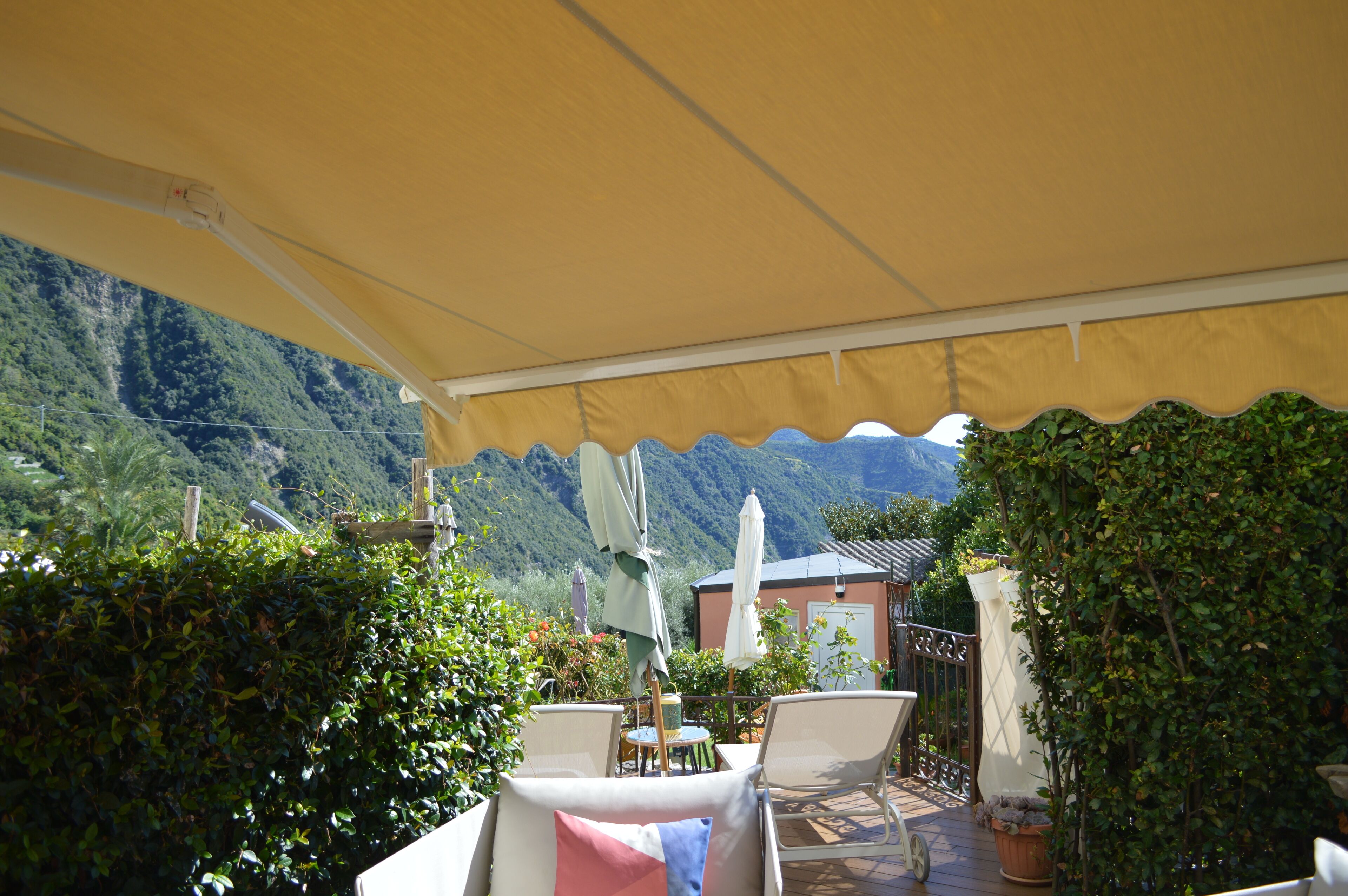 An outdoor patio with a yellow canopy, white chairs, and a table.