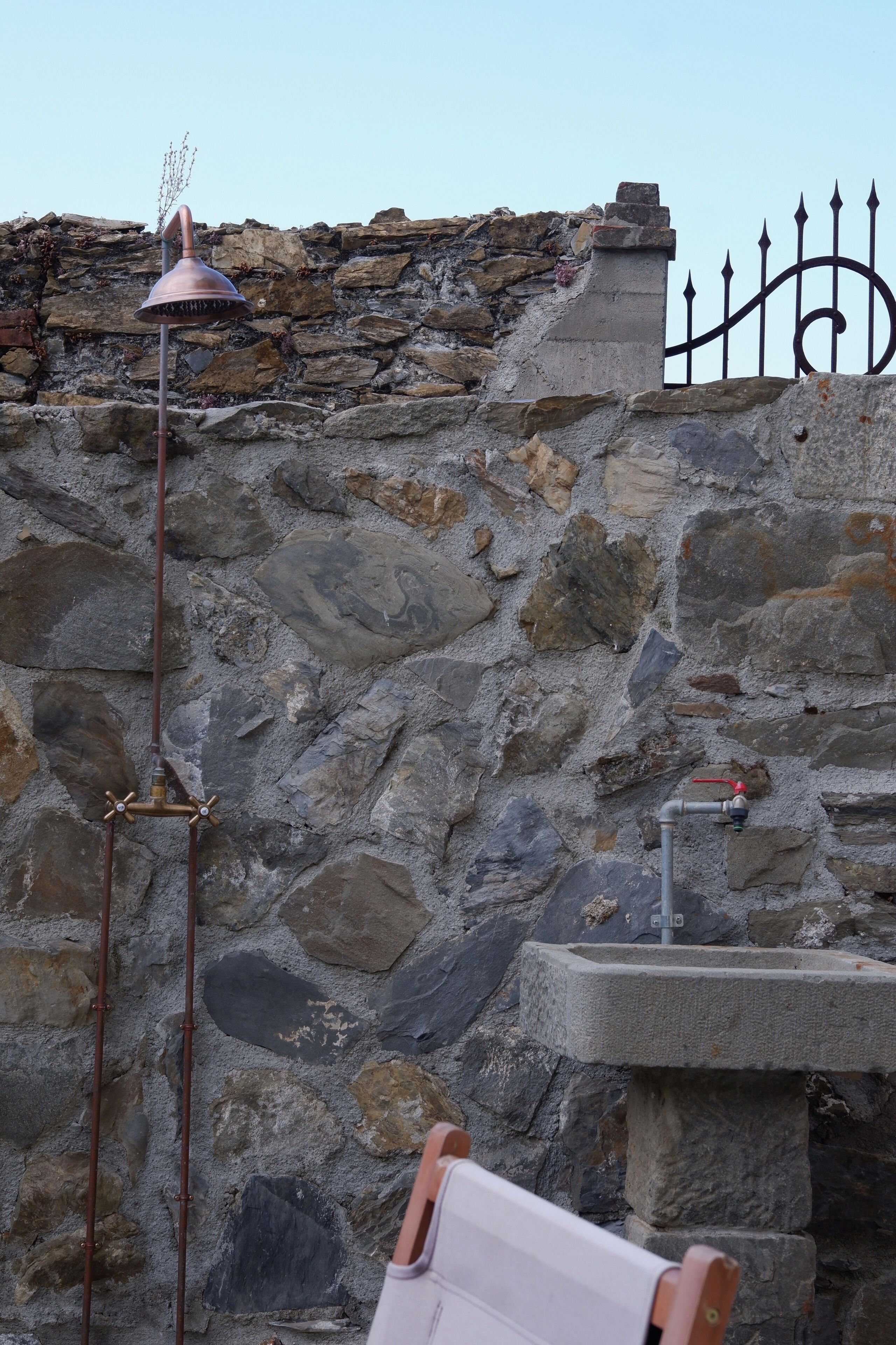 A stone wall with a metal lamp post and a metal fence.