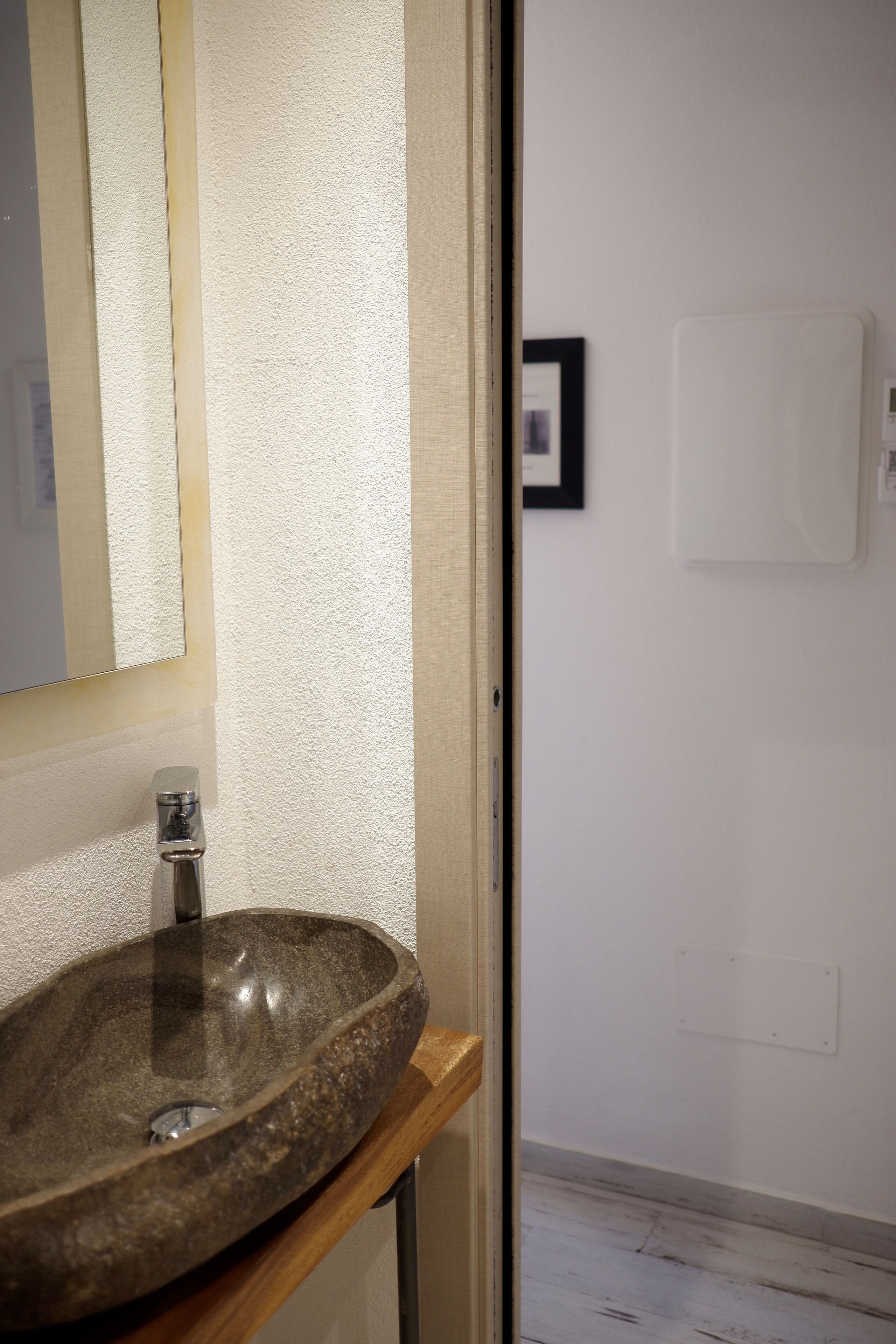 Un baño con un lavamanos de piedra, un espejo y un cuadro enmarcado en la pared.