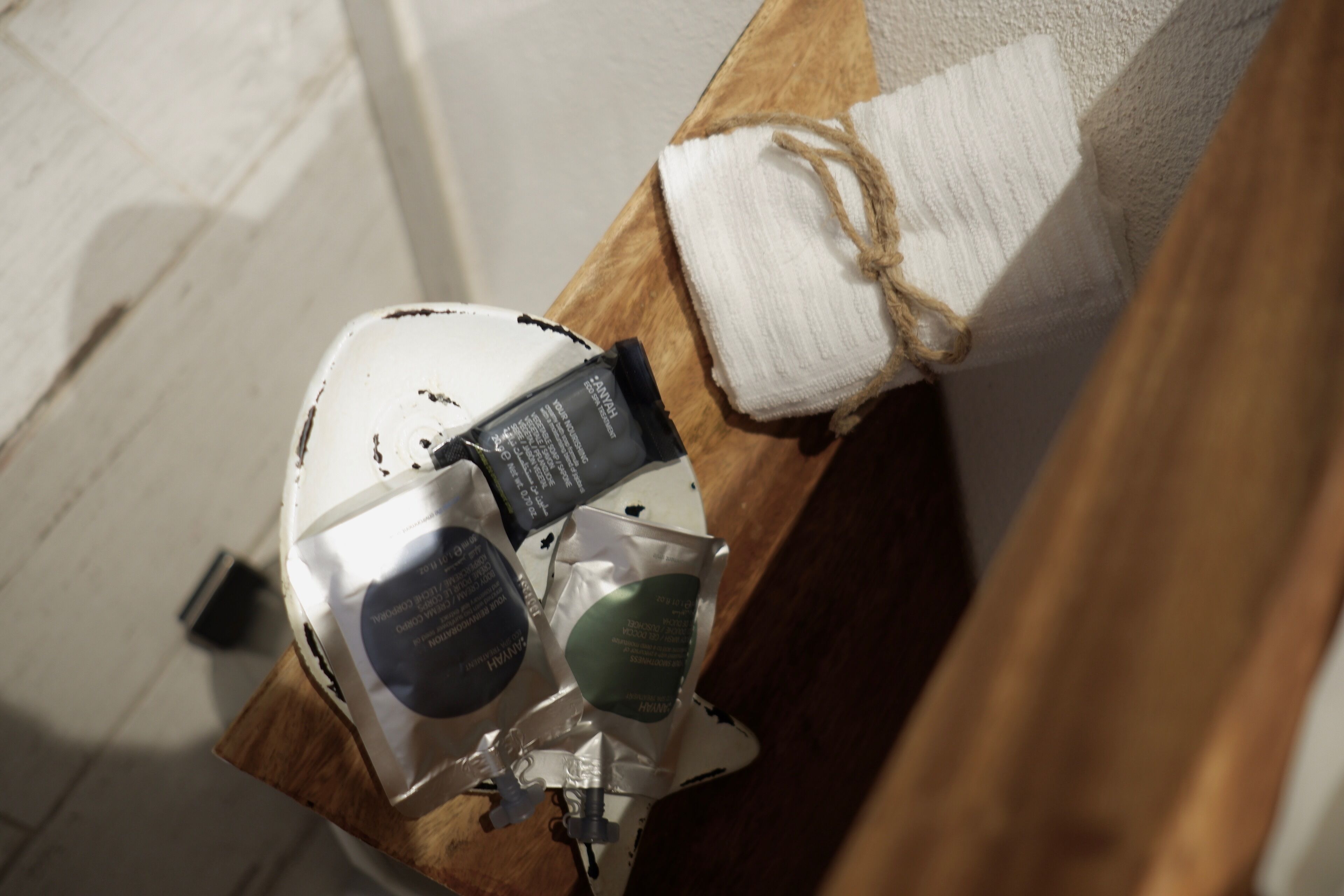 A wooden bench with a white towel and a small black object on it.