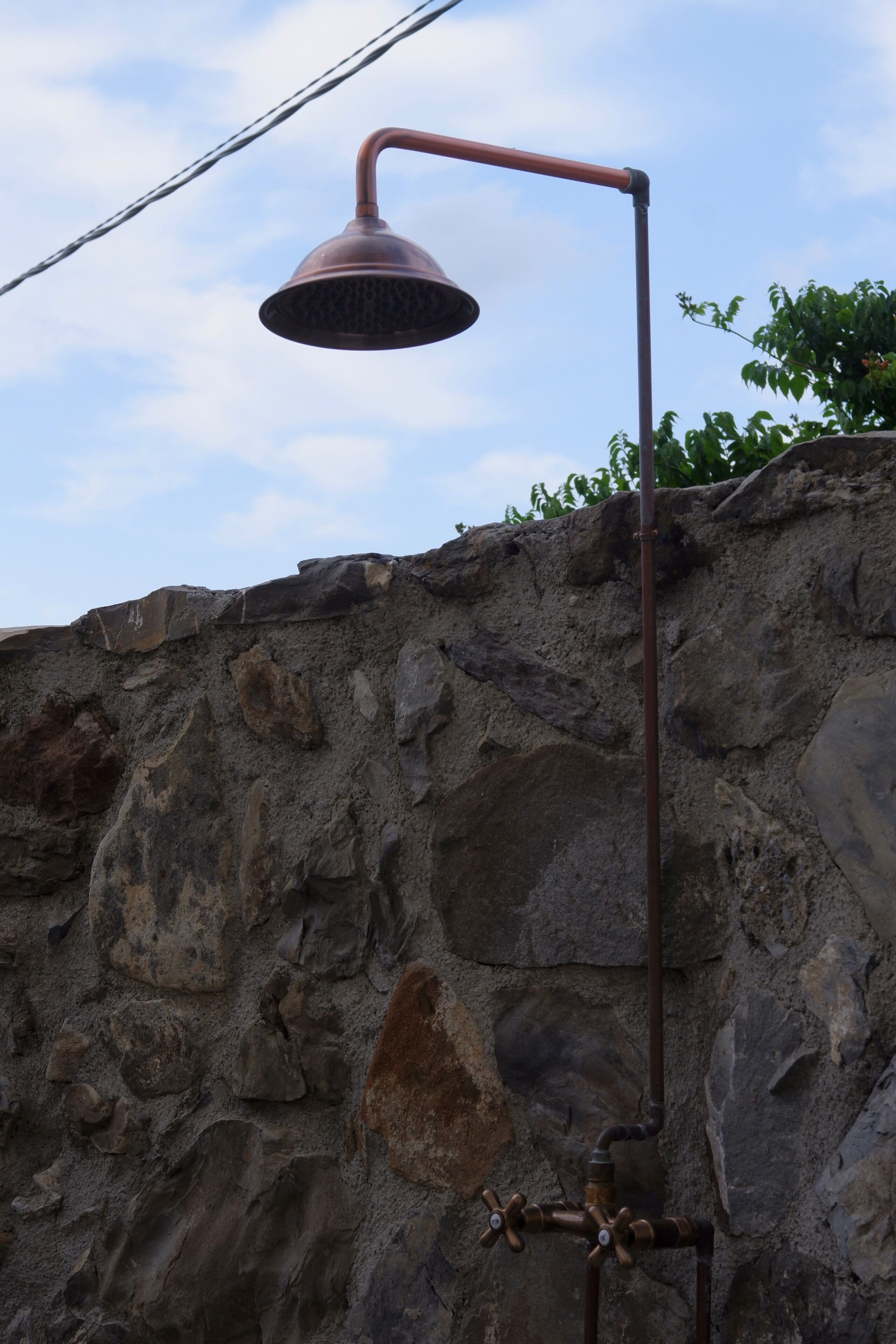 A metal showerhead mounted on a stone wall.