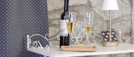 Una mesa con una botella de vino, dos copas, un candelabro y una cortina estampada.