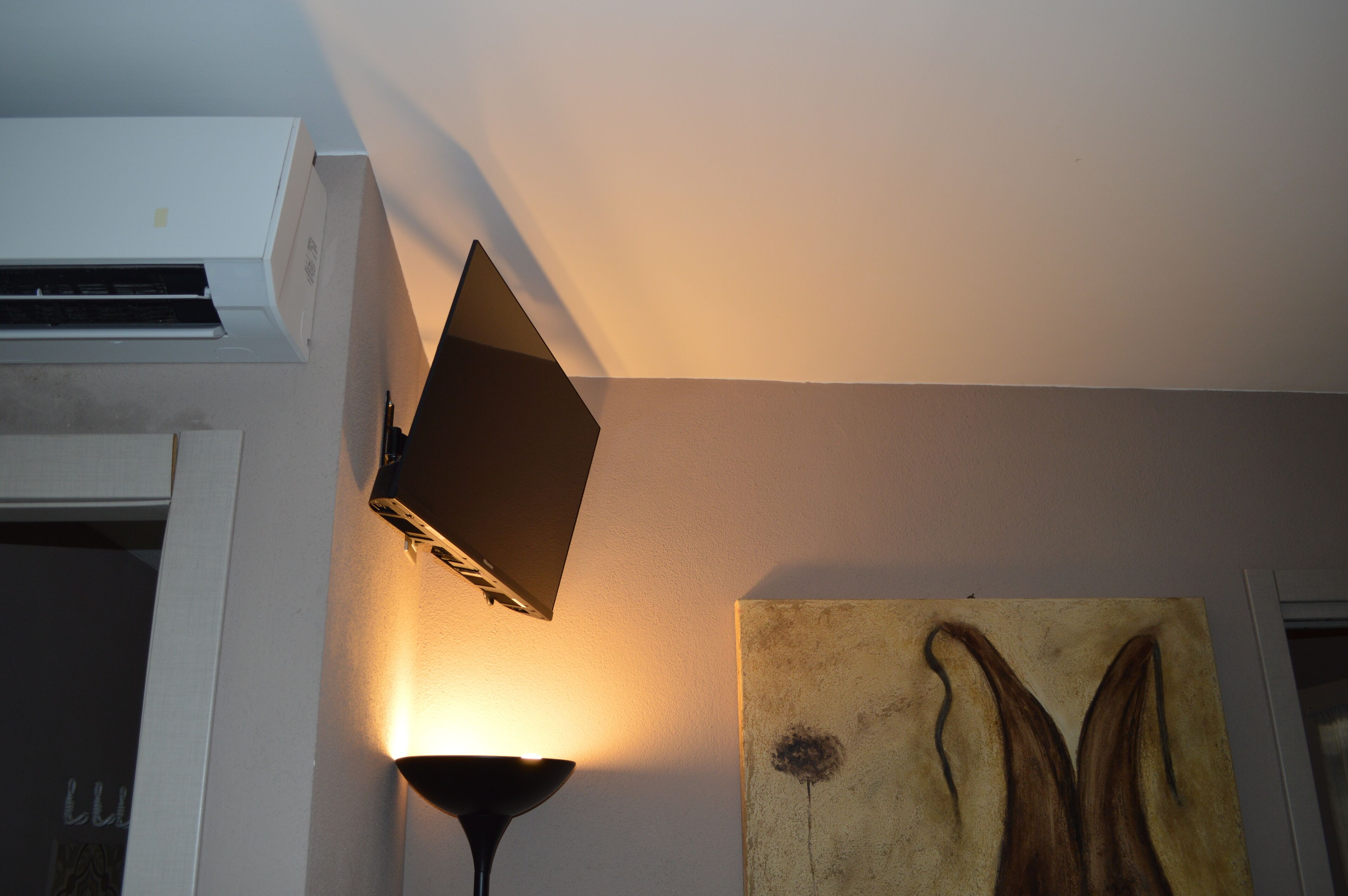 Una stanza con un condizionatore, una lampada a parete e un quadro.