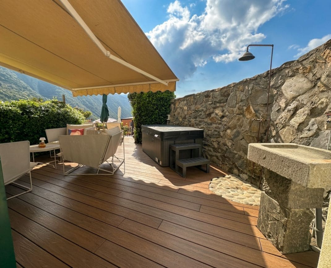 Un patio exterior con pared de piedra, una parrilla y una mesa con sillas.