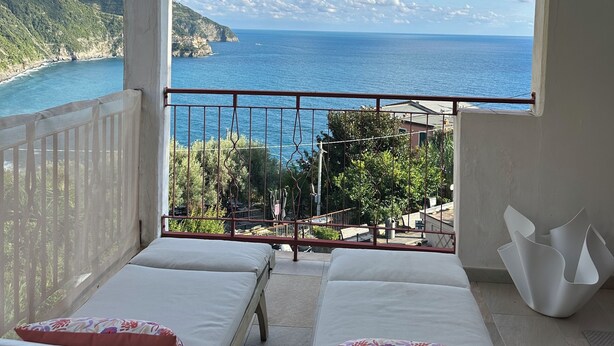 A balcony with two beds, a view of the sea, and a railing. - Madüneta 5 Terre Guesthouse (Vernazza)