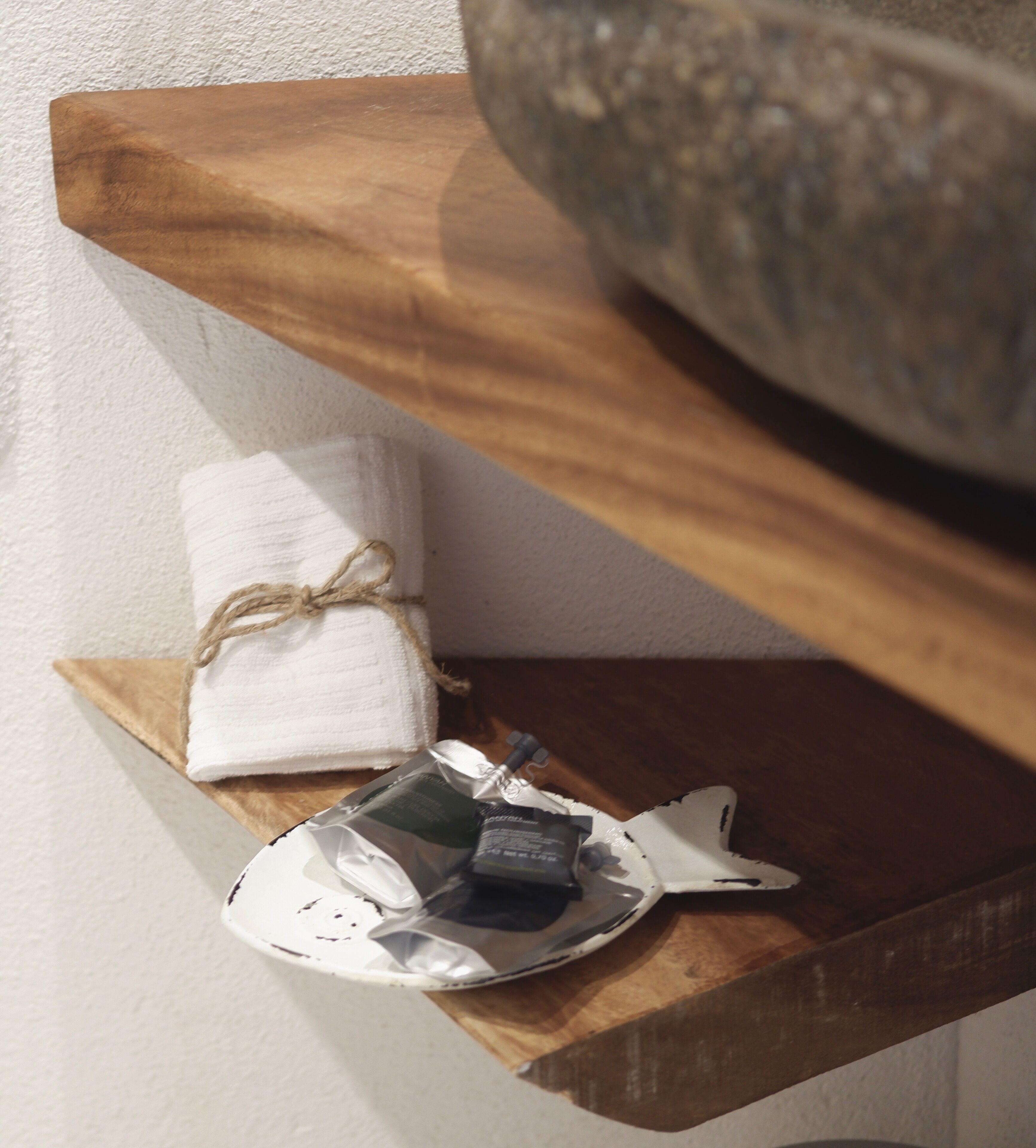 Una estantería de madera con una toalla blanca y un objeto envuelto en papel de aluminio.