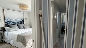 Ein Schlafzimmer mit einem Bett, einem an der Wand befestigten Spiegel und einem Holzschläger mit dem Wort 'BEACH'.