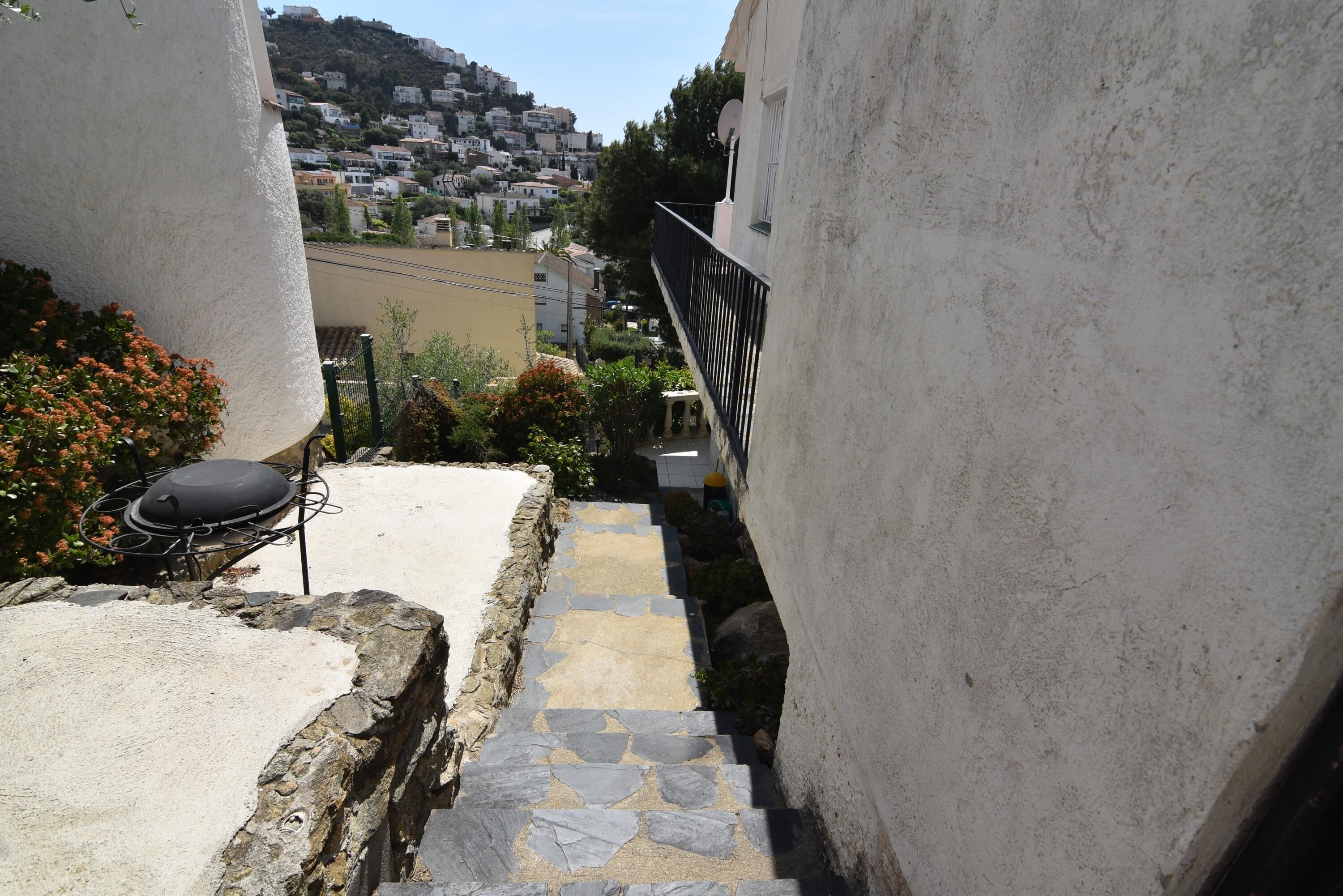 Una estrecha escalera de piedra que lleva a un balcón con una parrilla y mobiliario para exteriores.