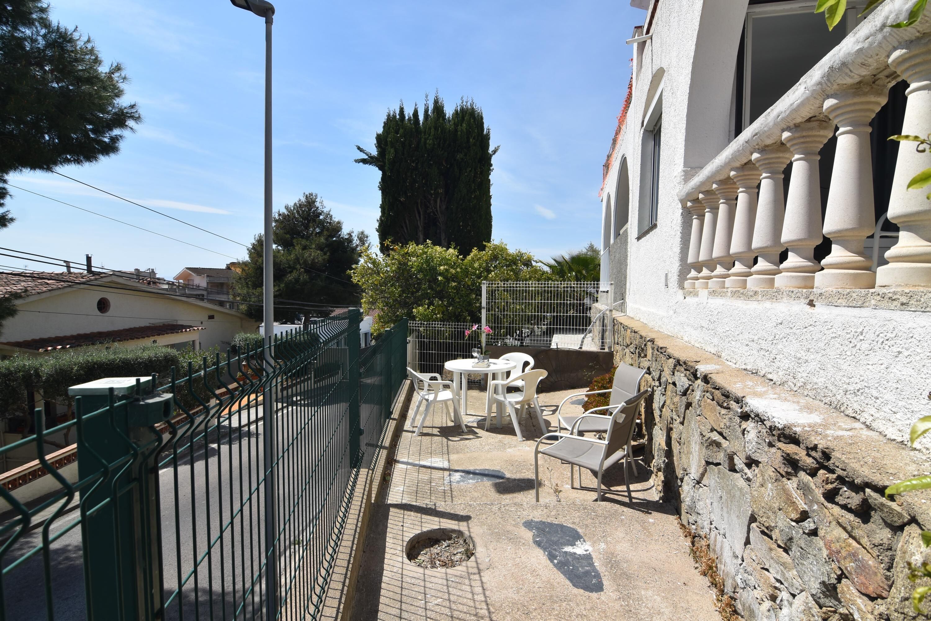 A courtyard with outdoor seating, a stone wall, and a tall tree.