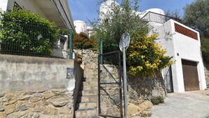 A stone staircase leading to a gated entrance with a metal gate and a signpost.