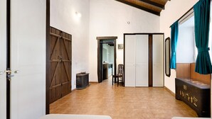 Ein Zimmer mit einem Bett, einer Holzkommode, einem Stuhl, einem Kleiderschrank und einer Tür zu einem anderen Raum.
