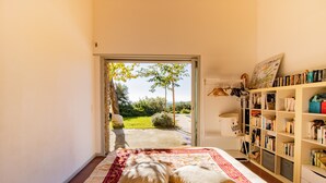 Ein Schlafzimmer mit einem Bett, einem Bücherregal und Blick durch eine offene Tür.