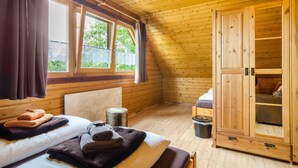 Una habitación de madera con una cama, un armario y una ventana con cortinas.