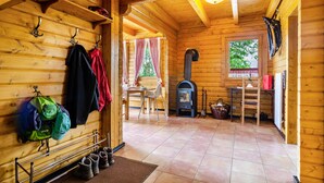 Interior de una cabaña de madera con chimenea, una zona de comedor y un zapatero.