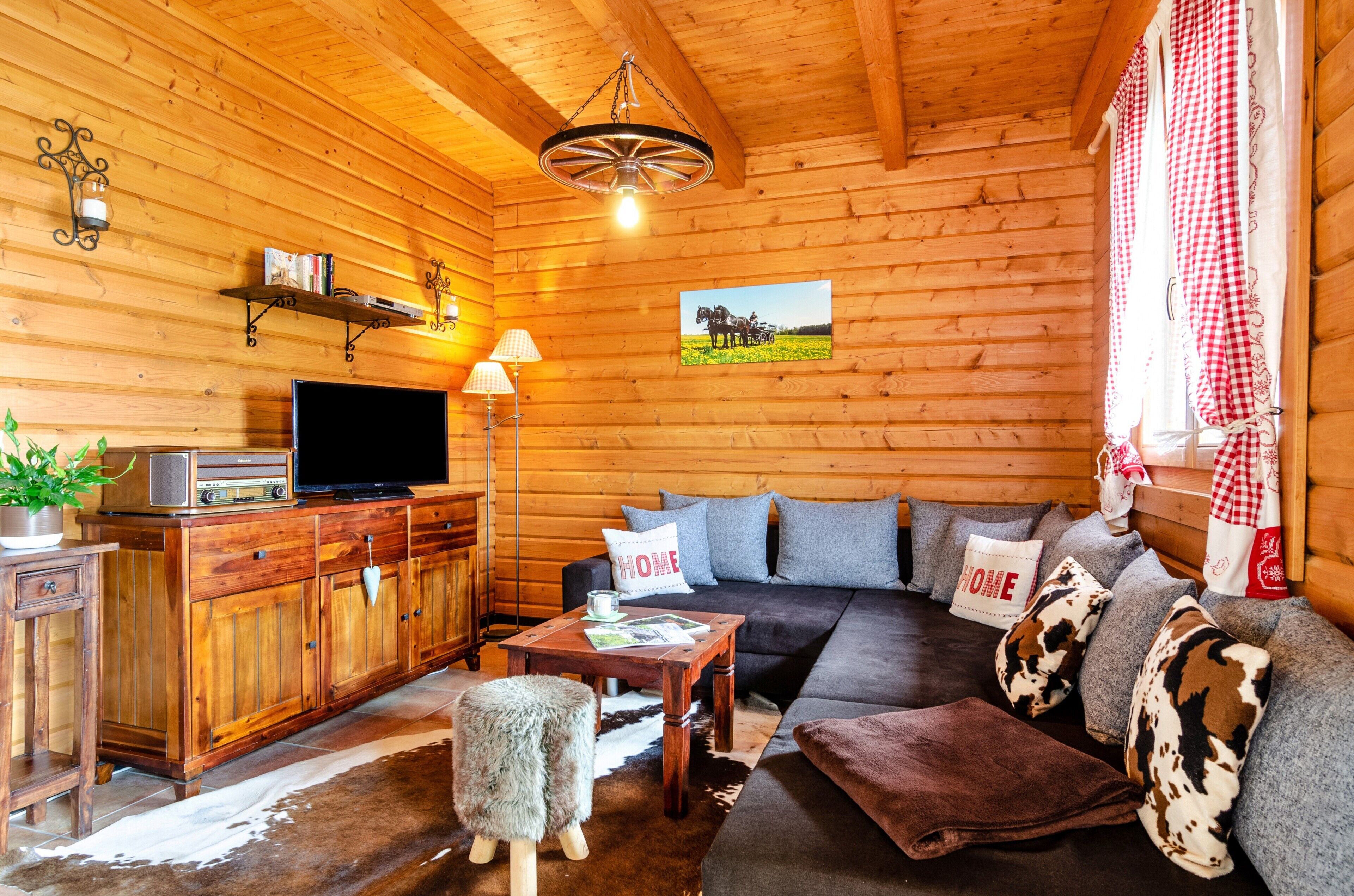 L’intérieur d’un chalet en bois comprend un canapé, un téléviseur, un meuble en bois et un tableau accroché au mur.