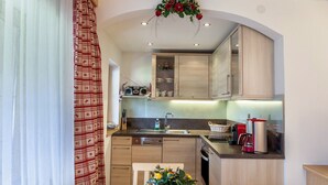 A kitchen with wooden cabinets, a sink, a coffee maker, and a dining area with a table and chairs.