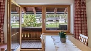 A room with a wooden ceiling, a sliding glass door, a table with a white tablecloth, and a potted plant.