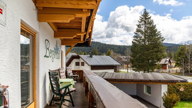 Eine Holterrasse mit Außenmöbeln, Blick auf die Berge und ein Gebäude mit der Aufschrift 'Bergkristall'.