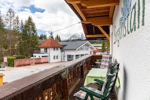 A balcony with wooden railings, a table with a green tablecloth, and a view of a mountain. - Apartment "Sterngucker Suite" with Mountain View, Shared Garden and Wi-Fi (Leutasch)