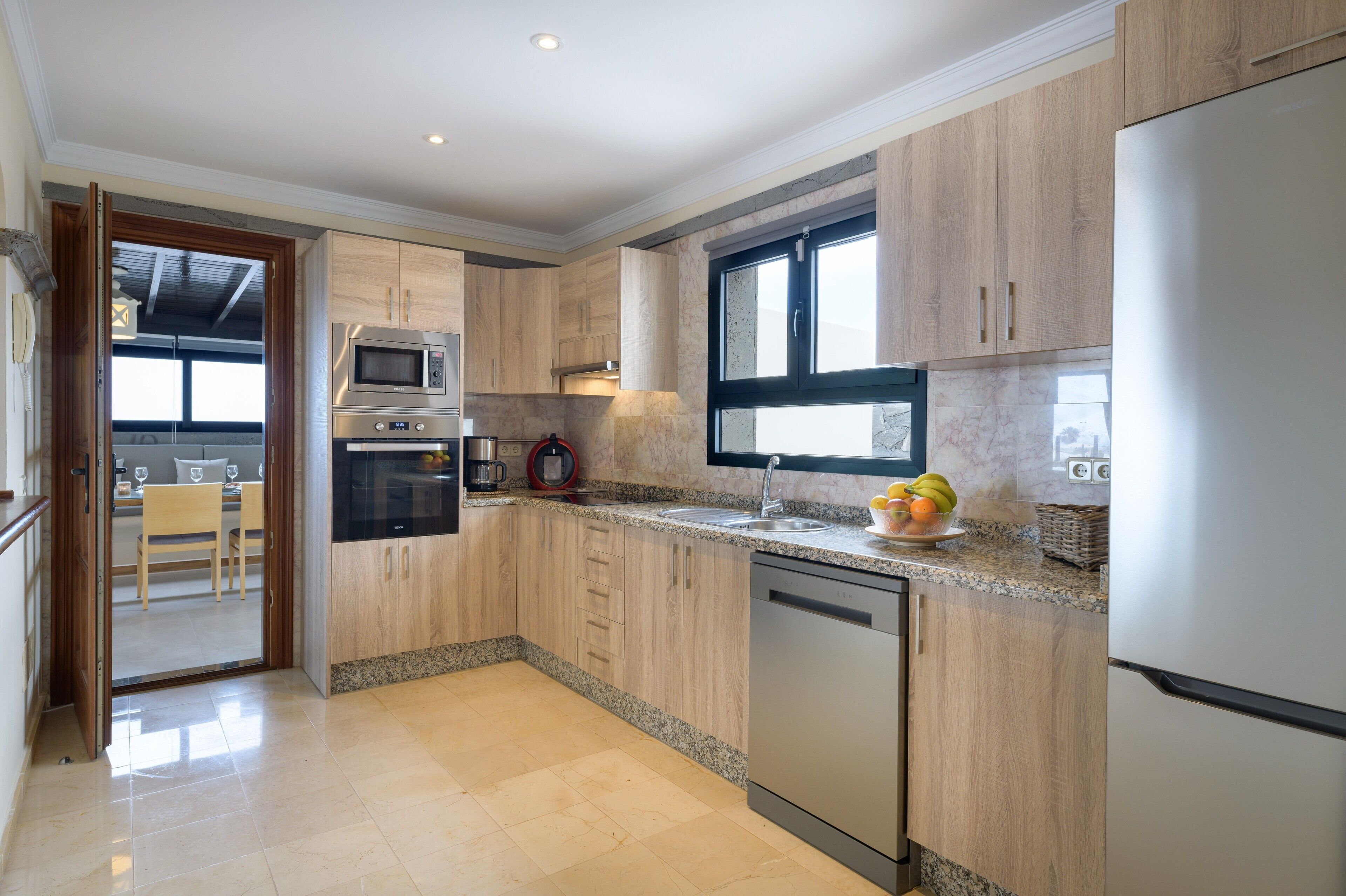 A modern kitchen with wooden cabinets, a stainless steel refrigerator, and a built-in oven.