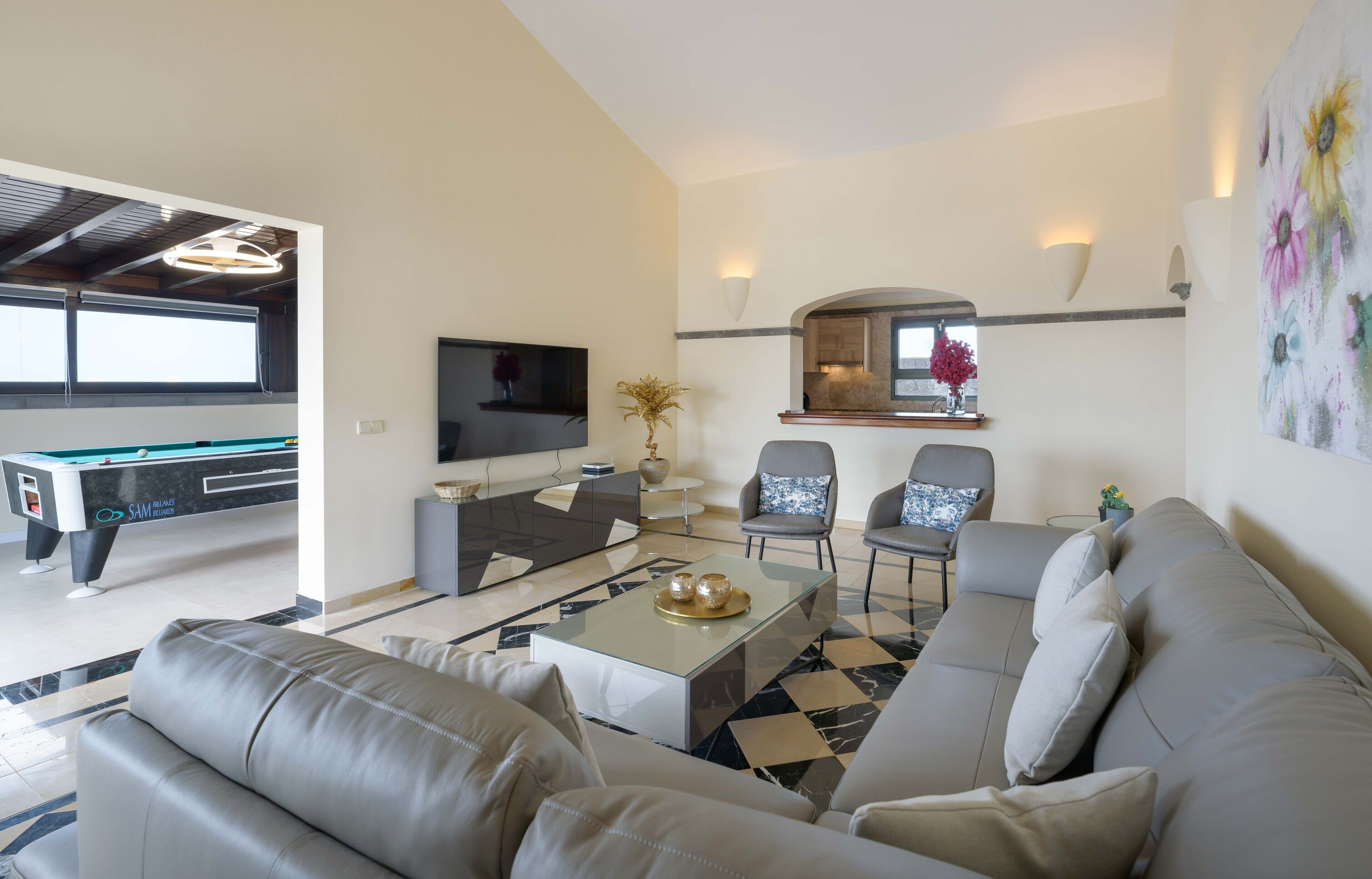 Una sala de estar moderna con sofá, mesa de centro, televisor y mesa de billar.