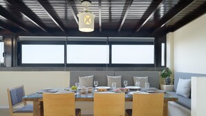 A dining area with a table set for four, a sofa, and a window with blinds.
