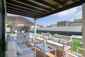 An outdoor patio with white furniture, a pool, and a mountain view.