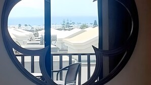 A circular window with a view of a balcony and buildings.