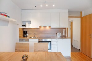 Une cuisine moderne avec des armoires blanches, un plan de travail en bois et un four encastré.