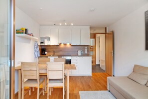 Een moderne keuken met witte kasten, een houten eettafel en stoelen.
