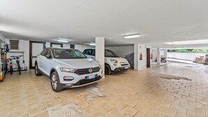A parking garage with two white cars, tiled floors, and a bike rack. - Holiday Home "Ca' Alessandra" with Private Terrace and Air Conditioning (Carloforte)