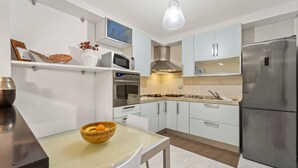 A modern kitchen with a built-in oven, microwave, and stainless steel refrigerator. - Holiday Home "Ca' Alessandra" with Private Terrace and Air Conditioning (Carloforte)