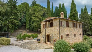A stone building with a stone staircase, a covered patio, and a view of tall trees. - Villa Podere Cafaggio with Private Pool, Terrace, and Air Conditioning (Monteverdi Marittimo)