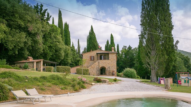 A stone house with a swimming pool, surrounded by lush greenery and tall trees. - Villa Podere Cafaggio with Private Pool, Terrace, and Air Conditioning (Monteverdi Marittimo)