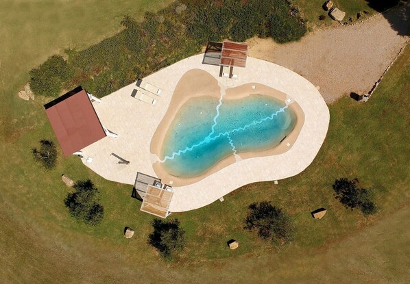 Vista aérea de una propiedad con piscina, terraza cubierta y una edificación separada.