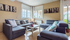 A living room with two grey sofas, a white coffee table, and a large window with a view of a garden.