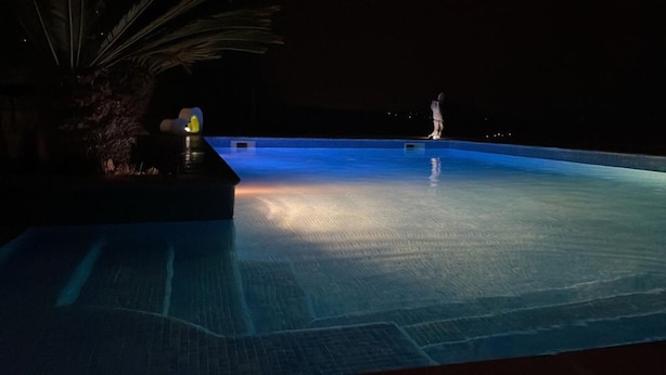 A nighttime swimming pool with a dark surrounding and minimal lighting.
