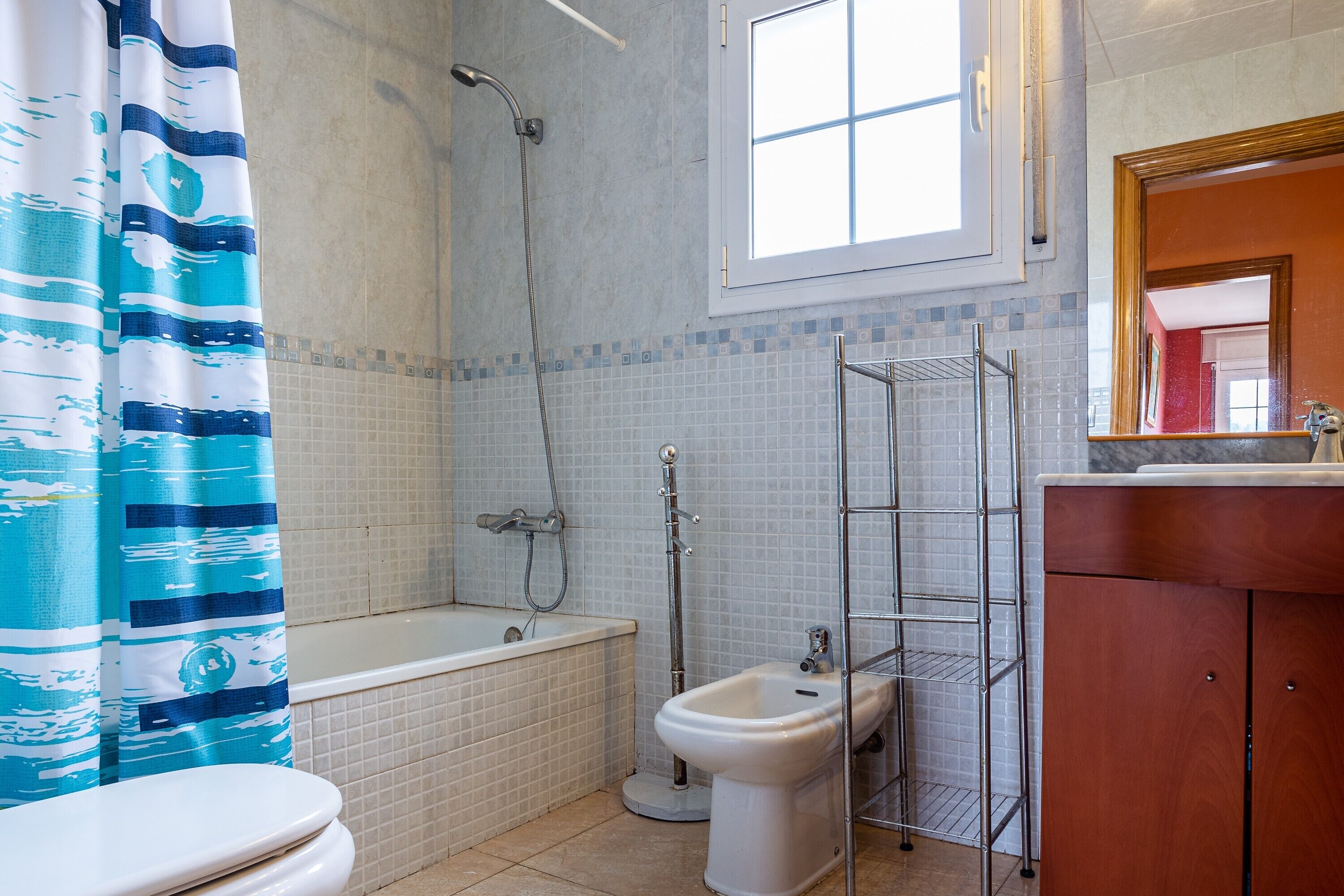 Et badeværelse med badekar, bruser, toilet og bidet.