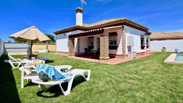 Una casa con patio, mobiliario exterior y piscina.