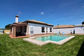 Une maison avec une piscine, une terrasse et un petit jardin.