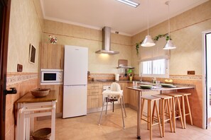 Une cuisine équipée d’un réfrigérateur, d’un four à micro-ondes et de tabourets en bois.