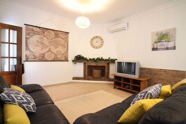 A living room with a fireplace, a large wall map, a clock, and a television.