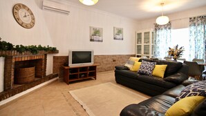 Una sala de estar con chimenea, televisor, sofá y cojines decorativos.