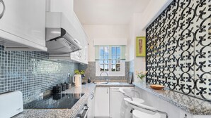 A modern kitchen with a granite countertop, white cabinetry, a built-in oven, and a window with a view. - Holiday Home "Un Regalo de Corazón" with Shared Pool & Wi-Fi (Orihuela)